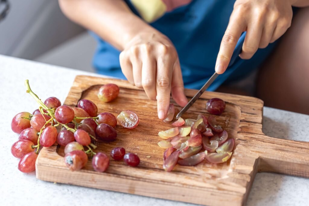 woman cuts grapes cutting board (1)